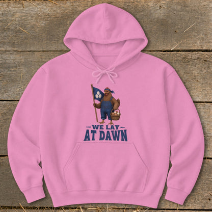 Pink hoodie with a chicken holding a flag and basket of eggs, text reads "WE LAY AT DAWN".