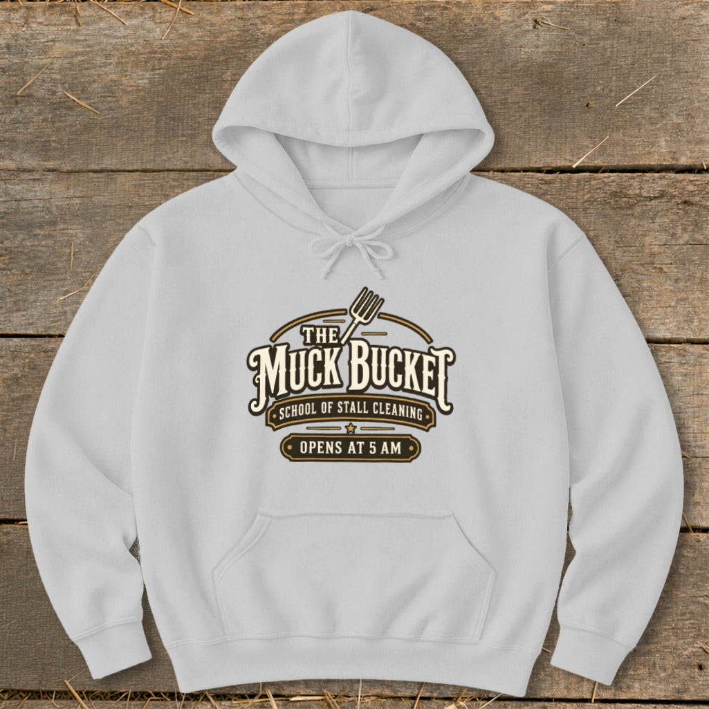 White hoodie with "The Muck Bucket School of Stall Cleaning Opens at 5 AM" logo.