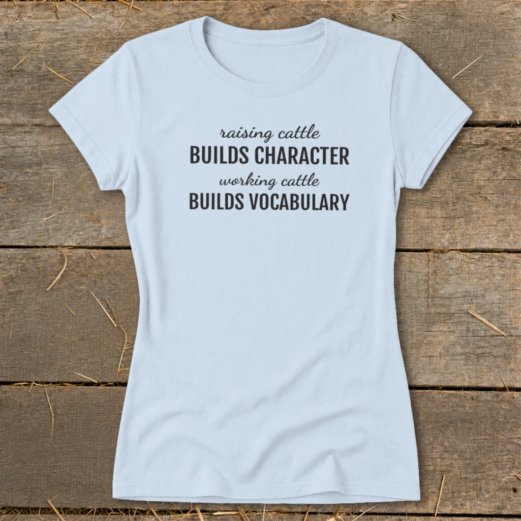 Light blue t-shirt with text "raising cattle BUILDS CHARACTER working cattle BUILDS VOCABULARY".