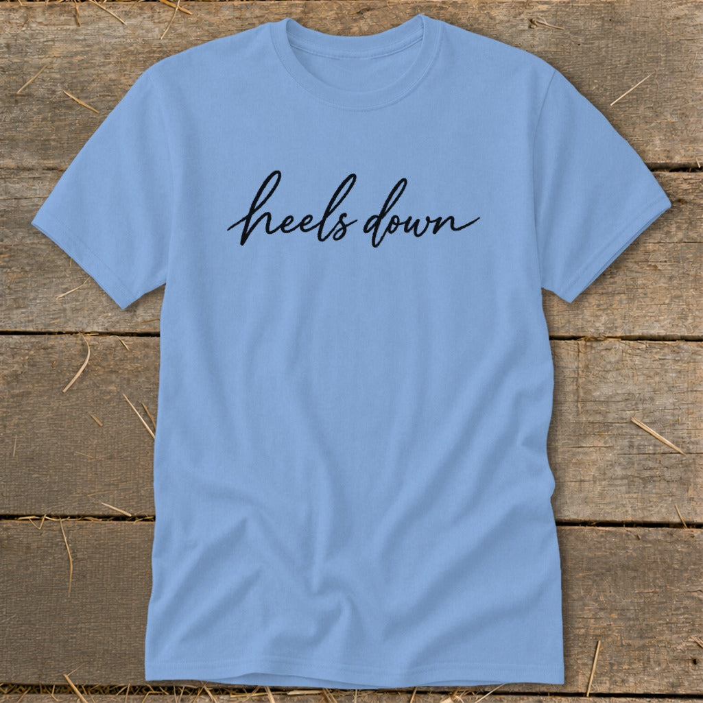 Light blue t-shirt with black cursive text "heels down"