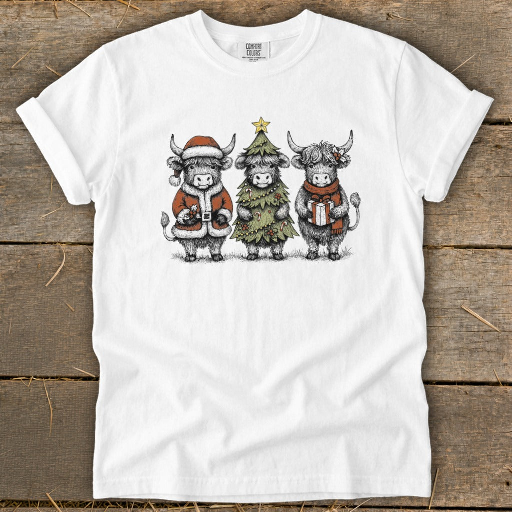Three highland cows in Christmas attire: Santa, Christmas tree, and gift.
