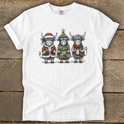 Three highland cows in Christmas attire: Santa, Christmas tree, and gift.
