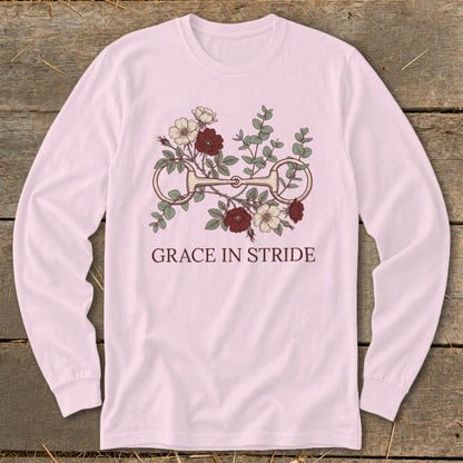 Pink long-sleeve shirt with a horse bit and floral design, reading "GRACE IN STRIDE."
