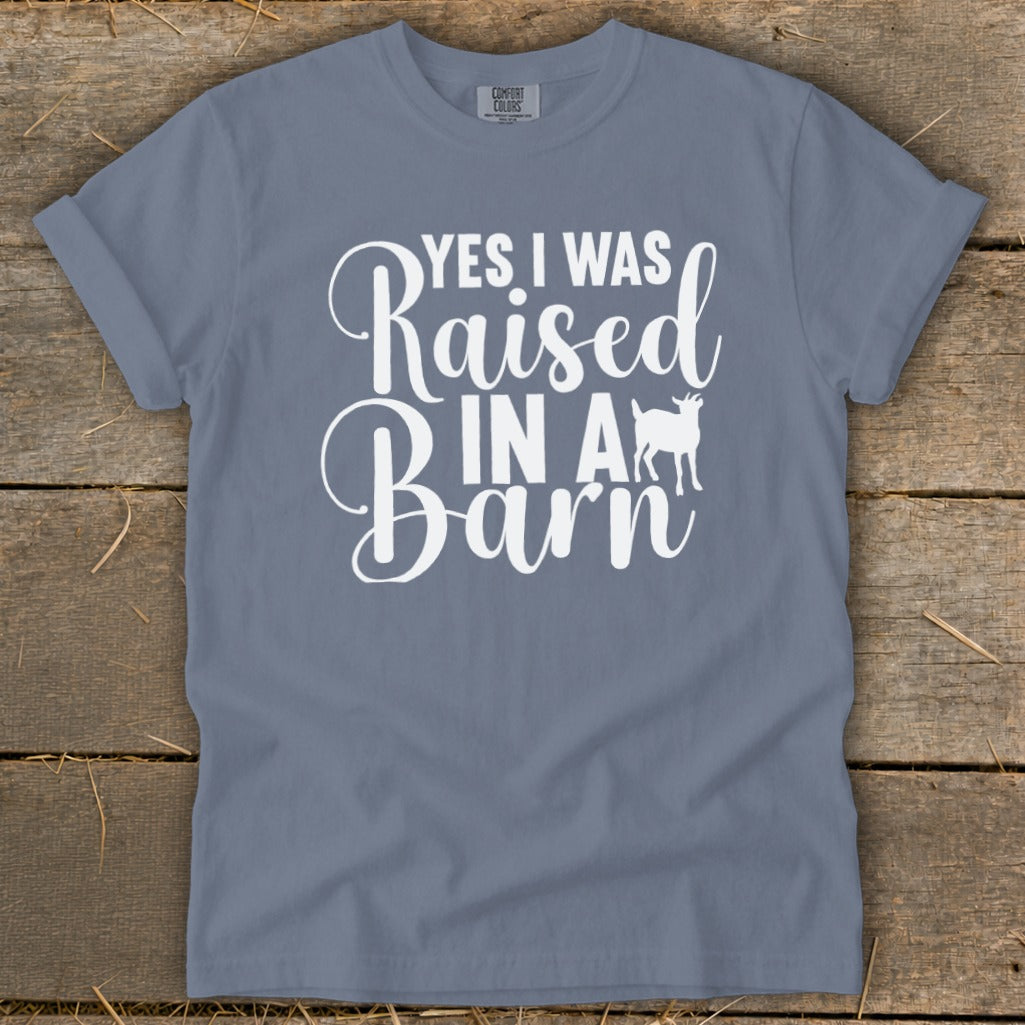 Blue t-shirt with white text "YES I WAS Raised IN A Barn" and a goat silhouette.