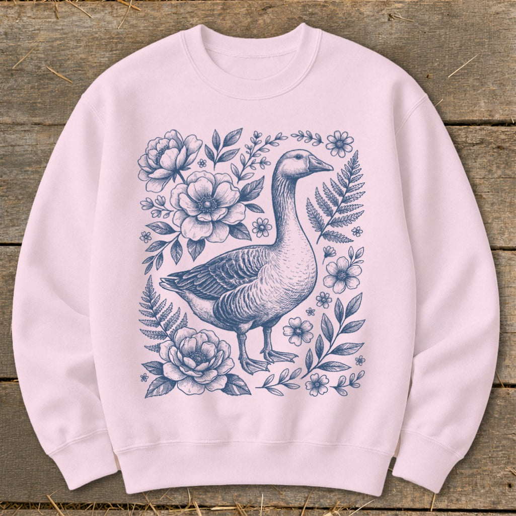 Pink sweatshirt with a blue line drawing of a goose surrounded by flowers and foliage.