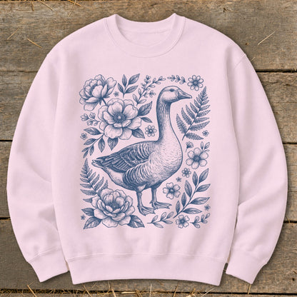 Pink sweatshirt with a blue line drawing of a goose surrounded by flowers and foliage.