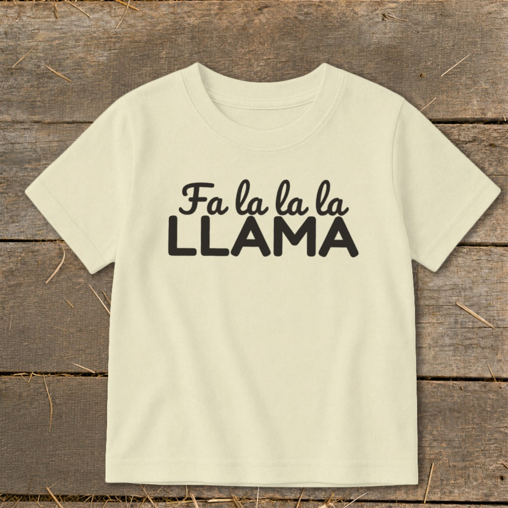 A light yellow children's t-shirt printed with black text reading Fa la la la la LLAMA.