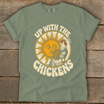 An olive green t-shirt with a vintage graphic of a rooster, a smiling sun, and the text Up With The Chickens.