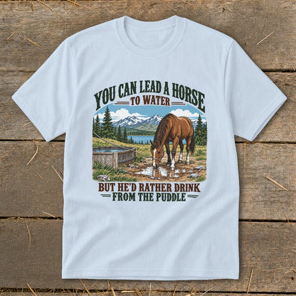 A light blue t-shirt with a graphic of a horse drinking from a puddle and humorous text.