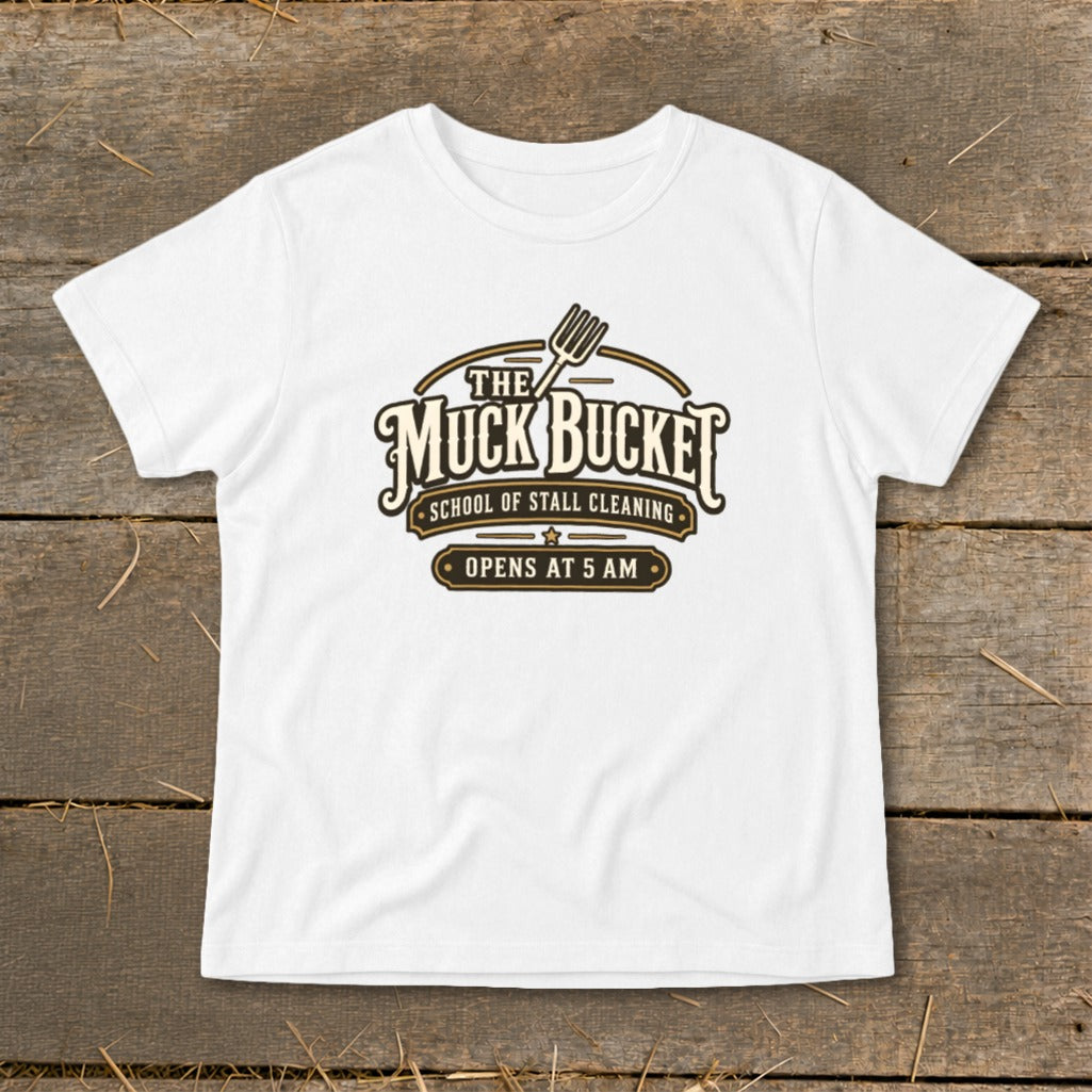 White t-shirt with "The Muck Bucket School of Stall Cleaning Opens at 5 AM" logo.