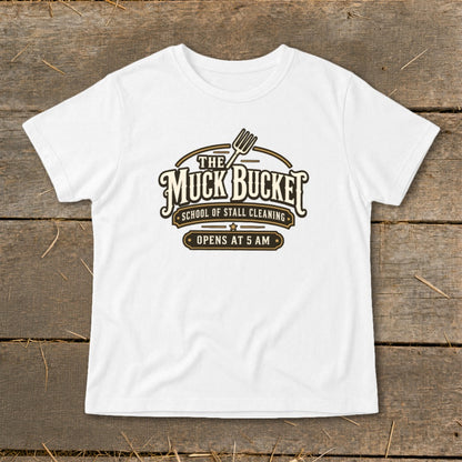 White t-shirt with "The Muck Bucket School of Stall Cleaning Opens at 5 AM" logo.