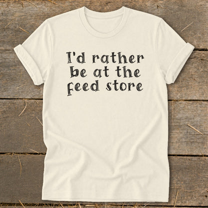 Cream t-shirt with black text that reads "I'd rather be at the feed store".