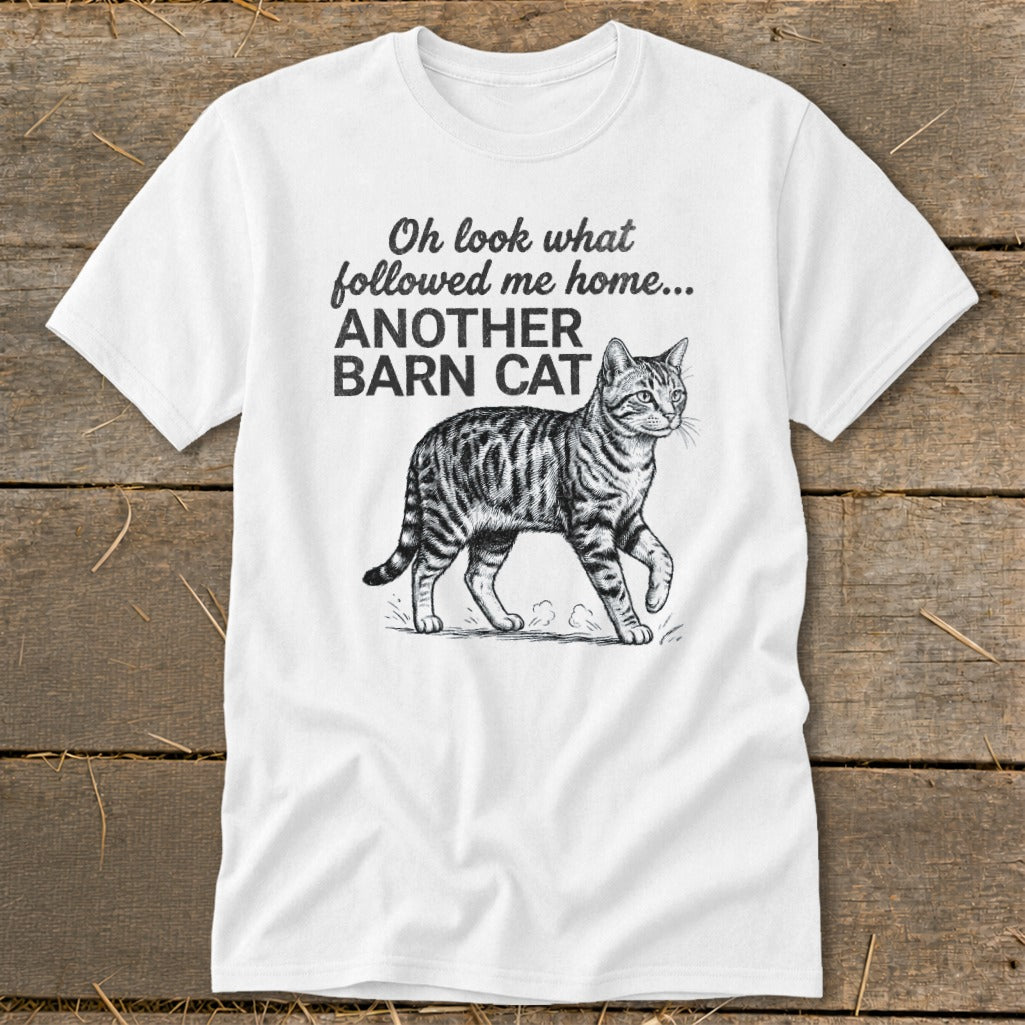 White t-shirt with text "Oh look what followed me home... ANOTHER BARN CAT" and a tabby cat illustration.