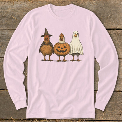 Three chickens dressed as a witch, a pumpkin, and a ghost on a pink long-sleeve shirt.