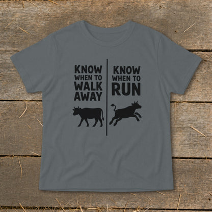 Gray t-shirt with black text "KNOW WHEN TO WALK AWAY" and "KNOW WHEN TO RUN" over cow silhouettes.