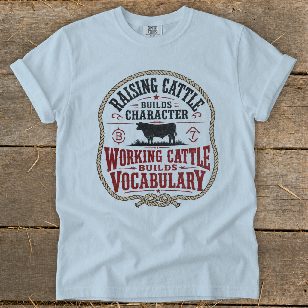 Light blue t-shirt with "Raising Cattle Builds Character, Working Cattle Builds Vocabulary" text and cow graphic.