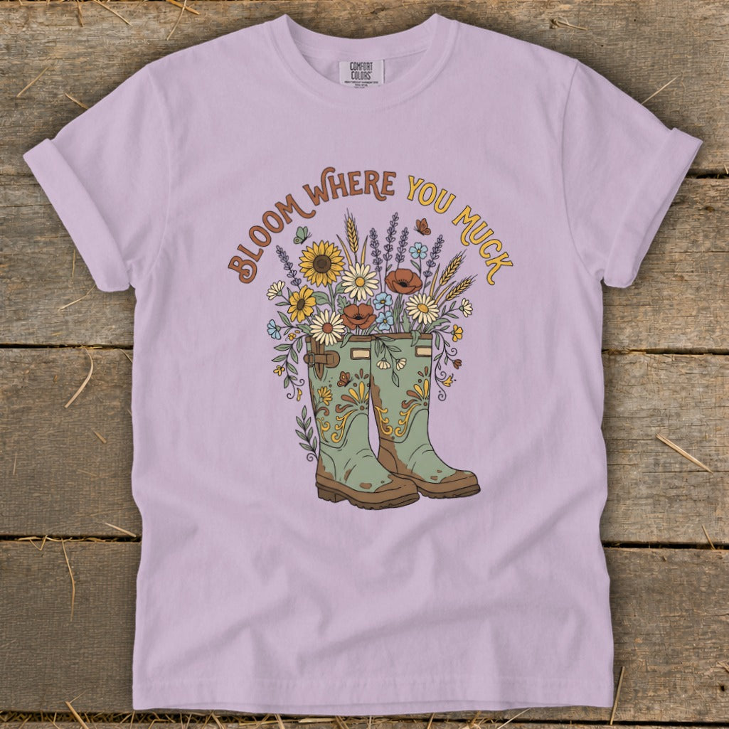 T-shirt with green boots overflowing with flowers and the text "Bloom Where You Muck".