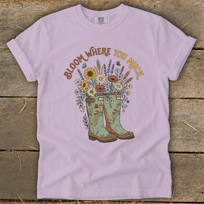 T-shirt with green boots overflowing with flowers and the text "Bloom Where You Muck".