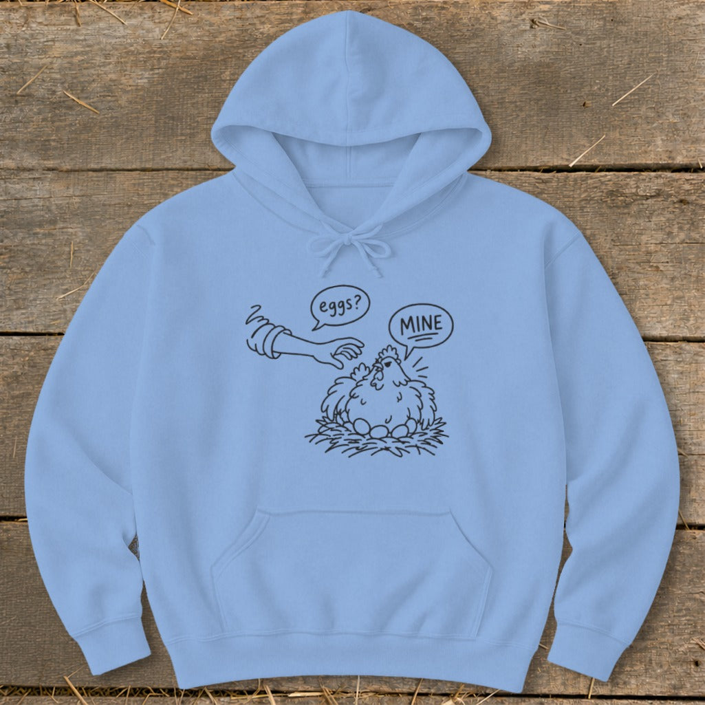 Light blue hoodie with black line art of a chicken protecting its eggs with "MINE" speech bubble.