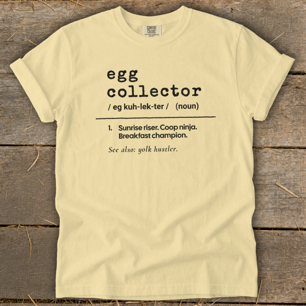 Light yellow t-shirt with black text defining "egg collector" as a breakfast champion.