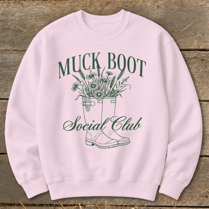 Pink sweatshirt with green "Muck Boot Social Club" text and floral boot design.