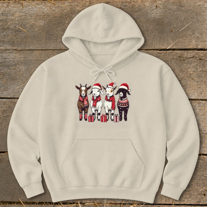 Four goats wearing Santa hats and scarves stand with presents on a cream hoodie.