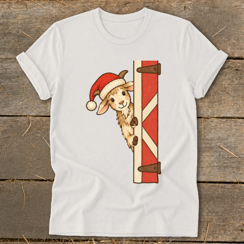 Christmas goat wearing Santa hat peeking from behind barn door on white t-shirt.