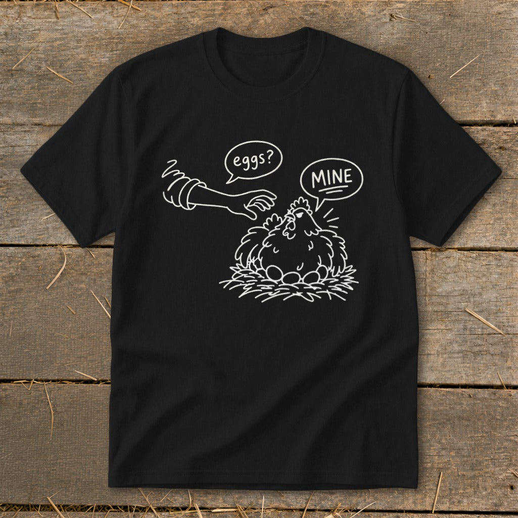 Black t-shirt with cartoon chicken guarding eggs and speech bubbles saying "eggs?" and "MINE".