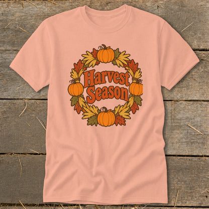 Peach t-shirt with retro "Harvest Season" text surrounded by pumpkins and autumn leaves.