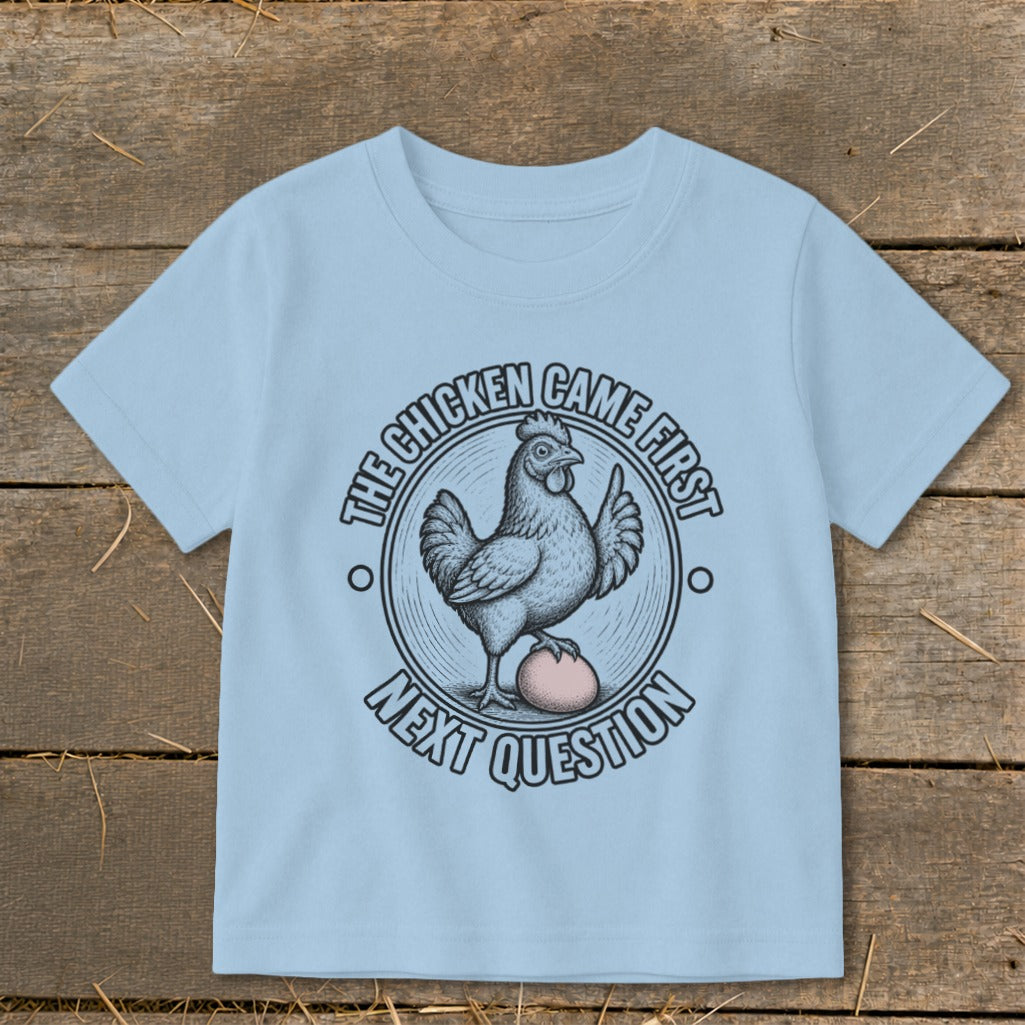 Light blue t-shirt with a chicken and egg graphic reading "The Chicken Came First, Next Question".