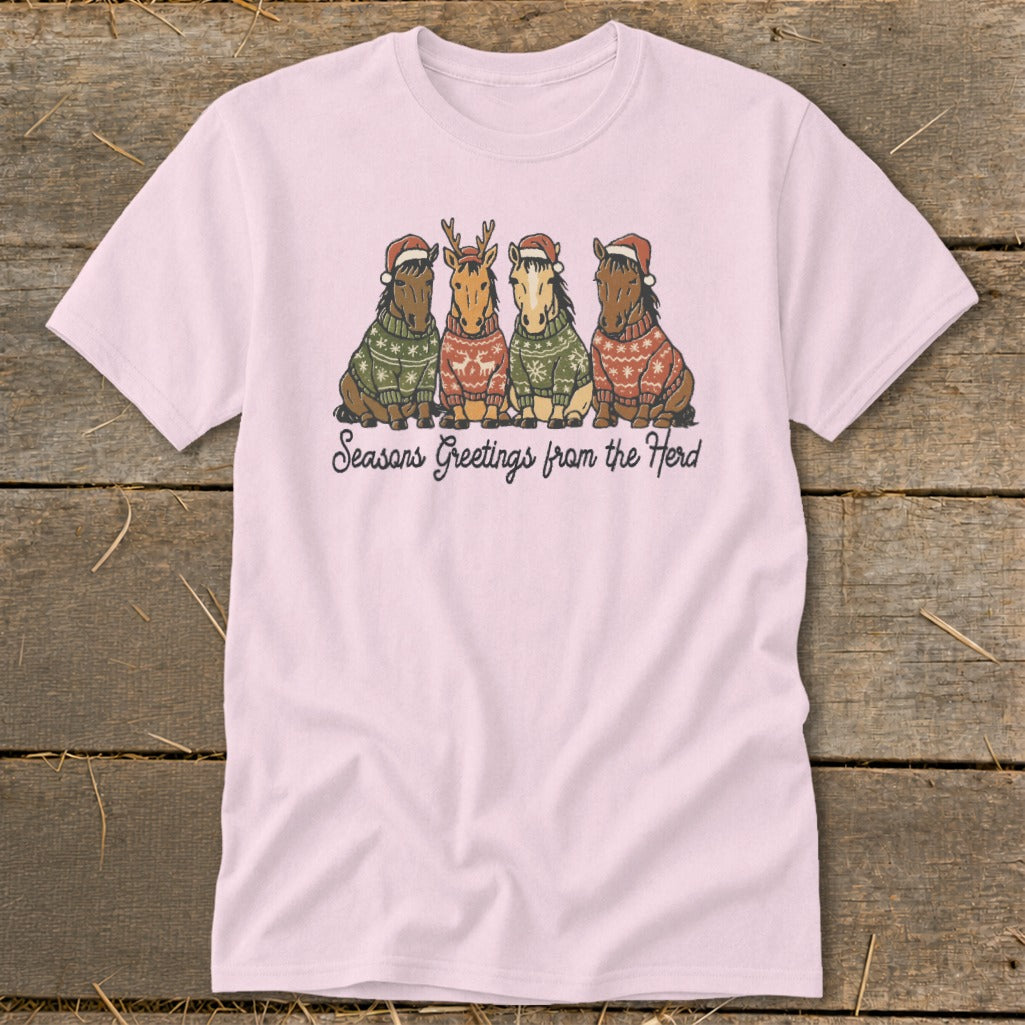 Pink t-shirt with four horses wearing sweaters and Santa hats, text says "Seasons Greetings from the Herd".