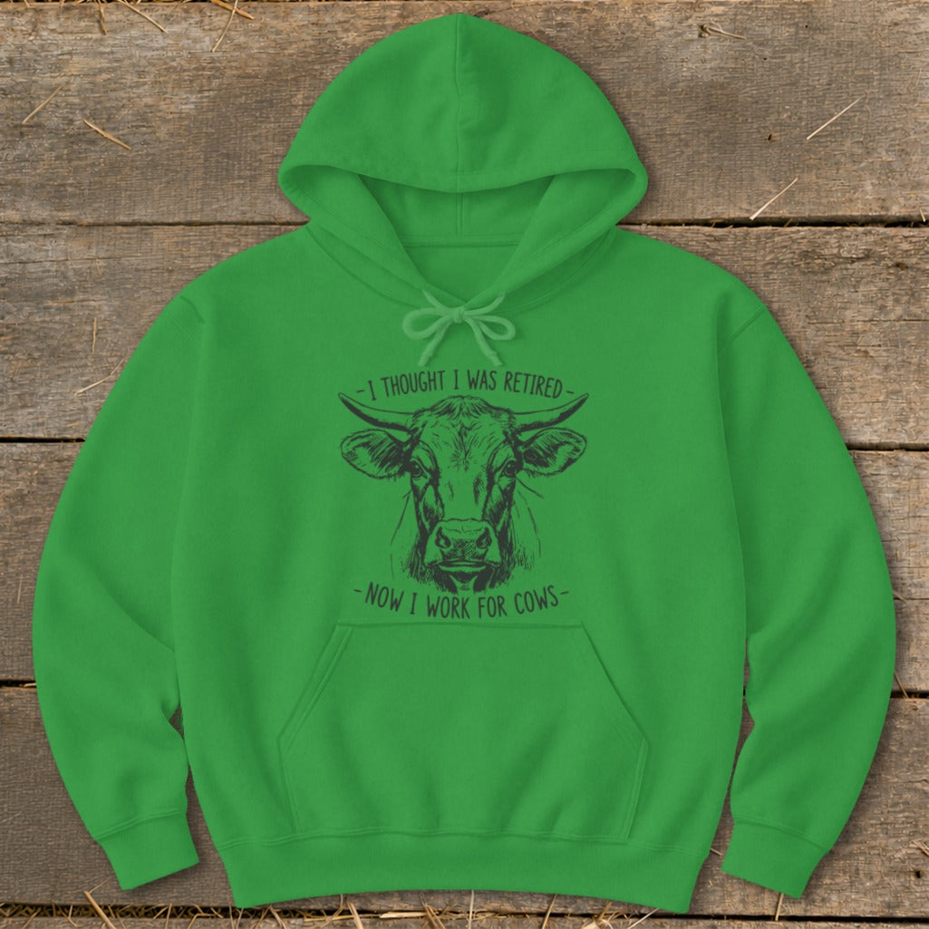 Green hoodie with a cow illustration and text "I thought I was retired - now I work for cows".