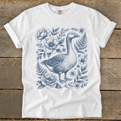 White t-shirt with blue line drawing of a goose surrounded by flowers and ferns.