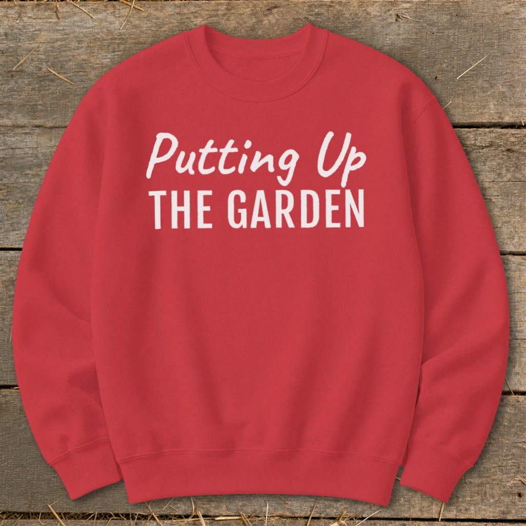 Red sweatshirt with white text reading "Putting Up THE GARDEN".