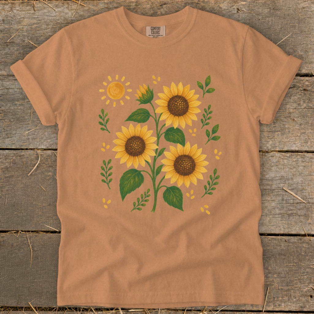 Peach t-shirt with illustration of sunflowers and a sun.