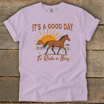 T-shirt graphic with horse, barn, sun, and text "It's a good day to ride a bay".