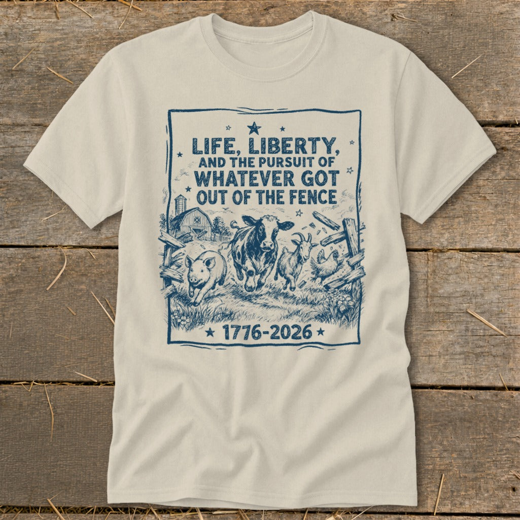 Cream t-shirt with blue graphic: "Life, Liberty, and the Pursuit of Whatever Got Out of the Fence 1776-2026" and farm animals.