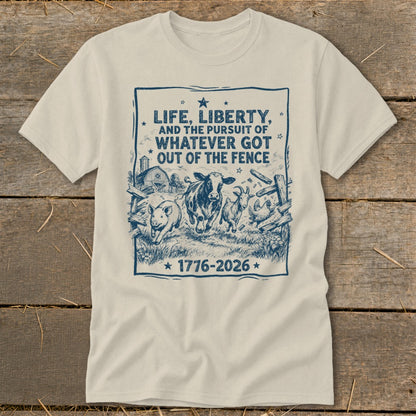 Cream t-shirt with blue graphic: "Life, Liberty, and the Pursuit of Whatever Got Out of the Fence 1776-2026" and farm animals.