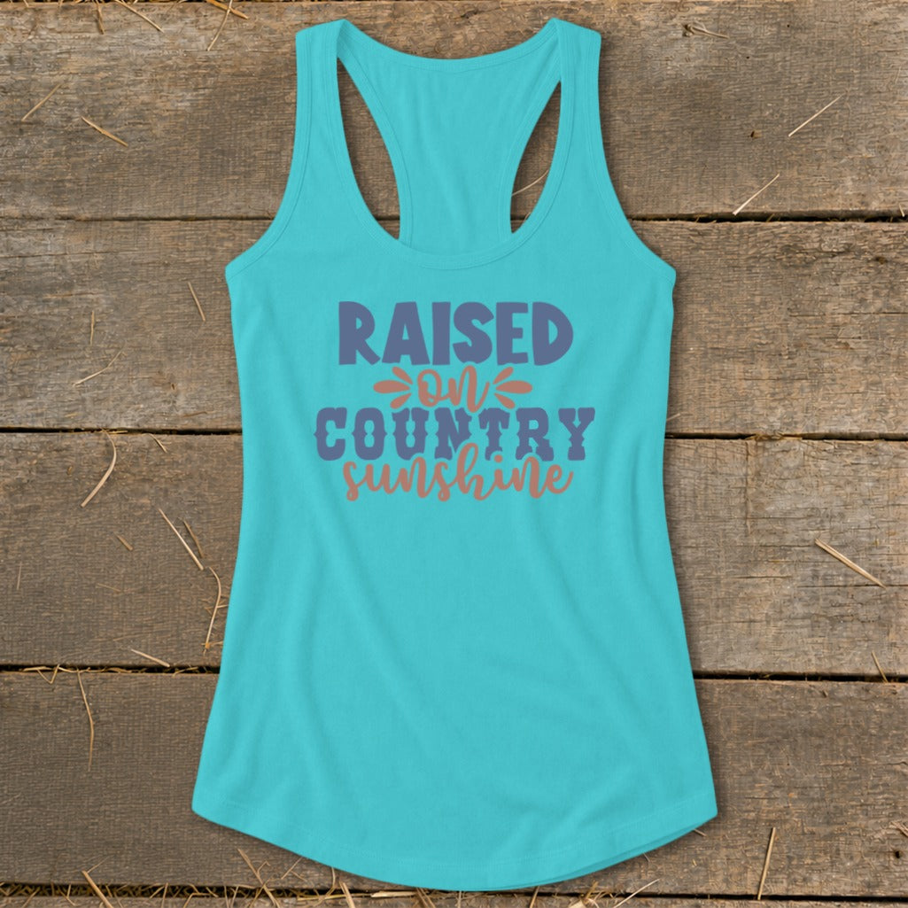 Turquoise tank top with "Raised on Country Sunshine" text in purple and orange.