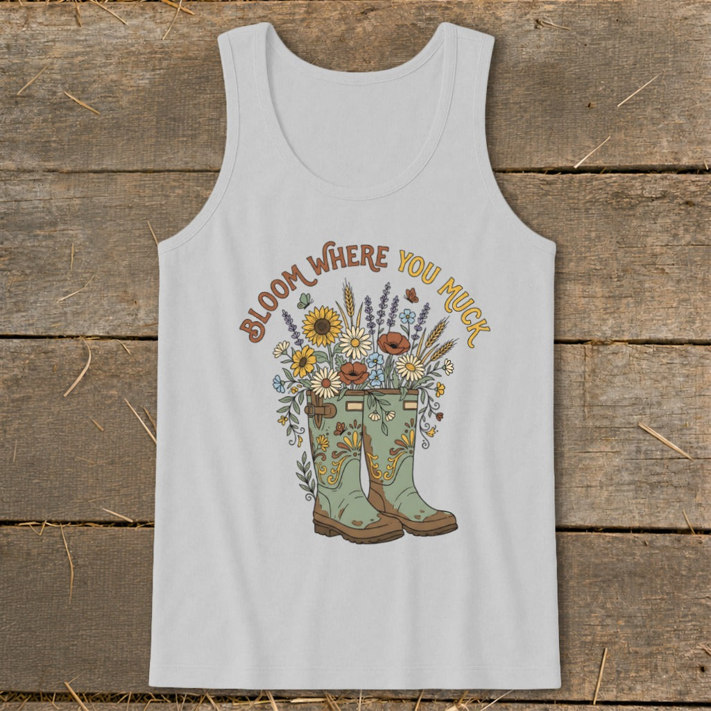 Light grey tank top with green boots and a floral bouquet, text reads "Bloom Where You Muck".