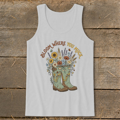 Light grey tank top with green boots and a floral bouquet, text reads "Bloom Where You Muck".