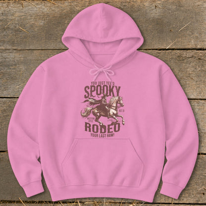 Pink hoodie with spooky rodeo design featuring a cowboy on a horse.
