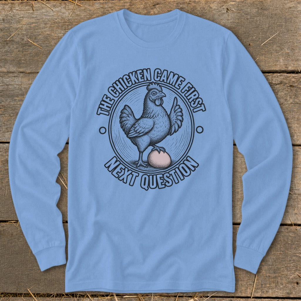 Light blue long sleeve shirt with a chicken and egg graphic saying "The chicken came first. Next question."
