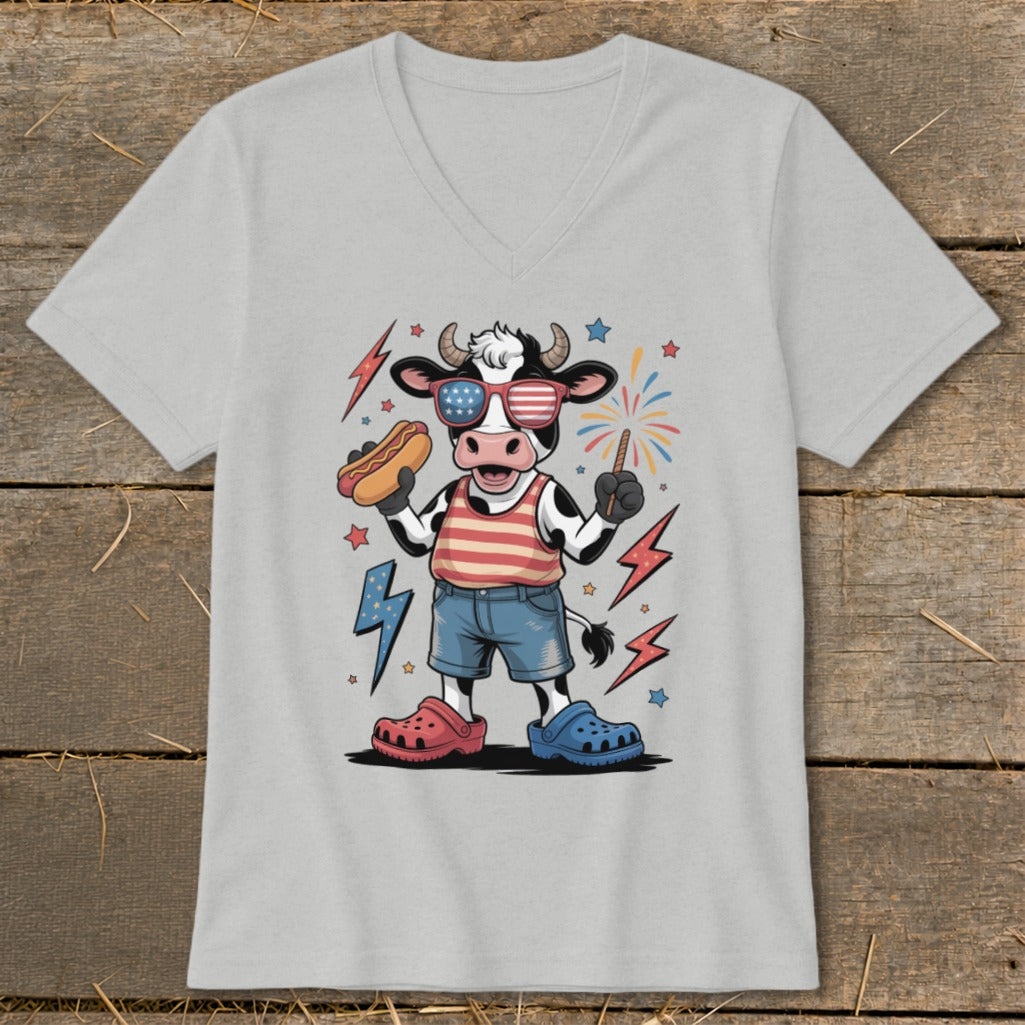 Cartoon cow in patriotic attire holding a hot dog and sparkler.