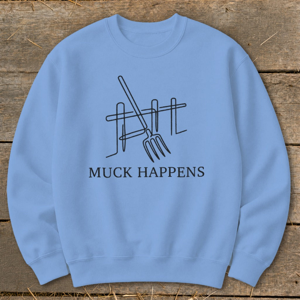 Light blue sweatshirt with black line art of a pitchfork and fence, and text "MUCK HAPPENS."