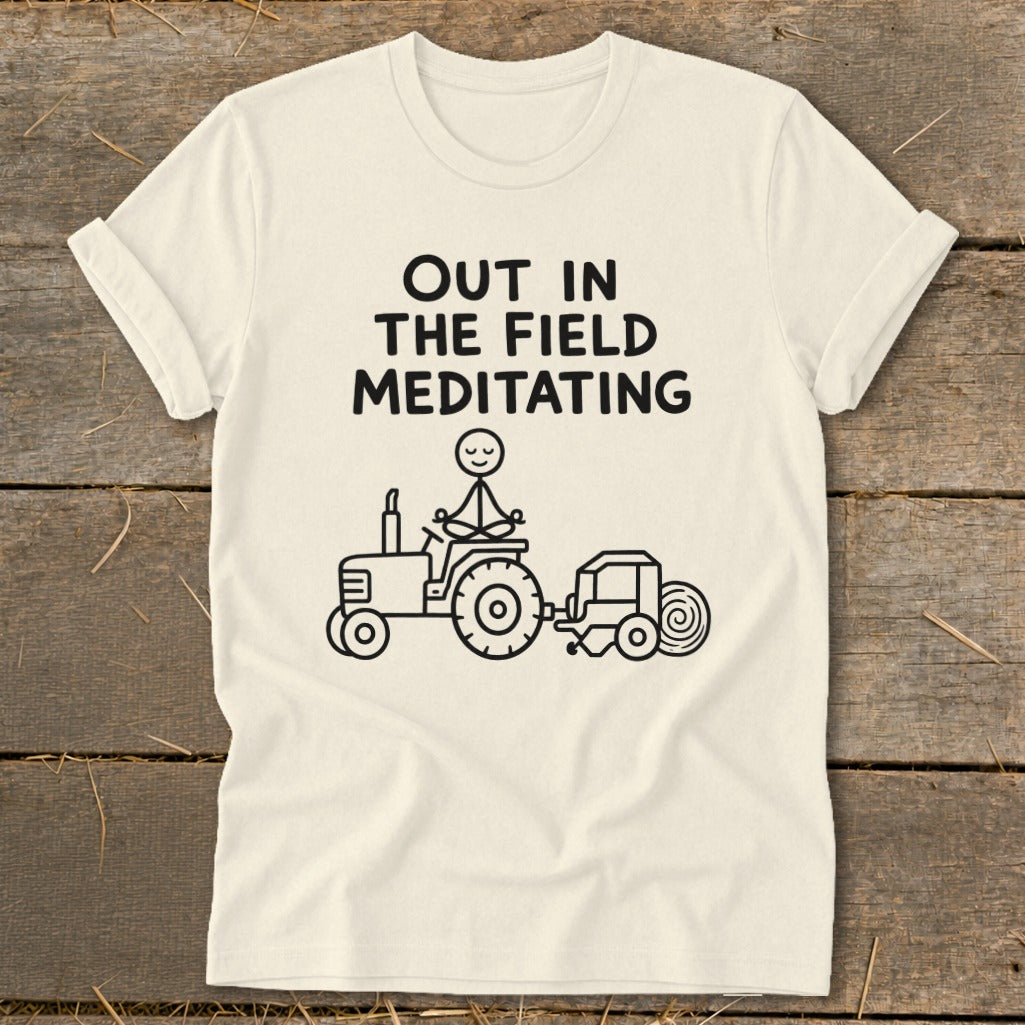 Cream t-shirt with black graphic of stick figure meditating on a tractor with a baler.