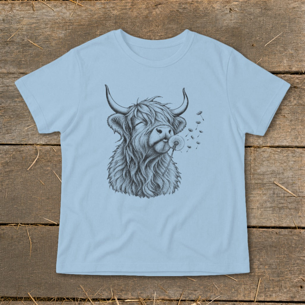 Light blue t-shirt with a black and white drawing of a Highland cow blowing a dandelion.