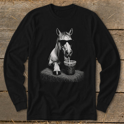 Horse wearing sunglasses drinks from a straw on a hay bale.