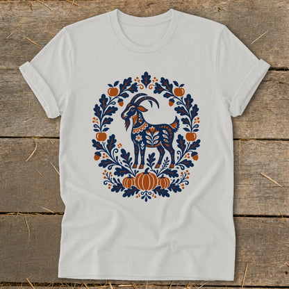 Light gray t-shirt with a folk-art graphic of a goat framed by autumn leaves, pumpkins, and acorns.