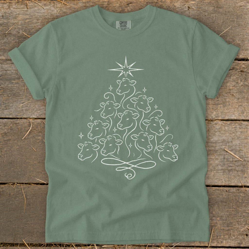 Green t-shirt with a white line drawing of cows forming a Christmas tree with a star on top.